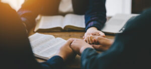 Christian group of people holding hands praying